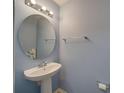Cozy half bathroom with a pedestal sink, round mirror, and neutral walls at 746 Elders Story Rd, Fort Mill, SC 29708