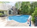 Backyard swimming pool with mature trees, a basketball hoop, and ample patio space for outdoor activities at 8704 Dartmoor Pl, Mint Hill, NC 28227