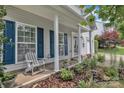 Inviting front porch with white columns, blue shutters, seating and beautiful landscaping at 1017 Chalk Hill Ln, Charlotte, NC 28214