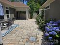 Charming patio with stone pavers, blooming hydrangeas, and an outdoor dining area, perfect for entertaining guests at 1112 Avalon Pl, Stallings, NC 28104