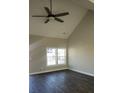 Open living area with a vaulted ceiling, a ceiling fan, a large window, and dark wood-look flooring at 1303 W Gold Street Ext, Kings Mountain, NC 28086