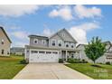 Beautiful two-story home featuring a manicured lawn, three car garage, and welcoming curb appeal at 7027 Waterwheel St, Concord, NC 28025