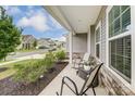 Inviting covered porch with seating area overlooking the street and landscaped garden at 7027 Waterwheel St, Concord, NC 28025