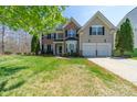 Charming two-story home features a manicured lawn and a two-car garage at 7719 Whisperingwood Dr, Harrisburg, NC 28075