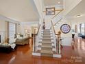 Bright foyer with hardwood floors, staircase with white railings, and an open view to the living and dining areas at 7719 Whisperingwood Dr, Harrisburg, NC 28075
