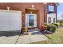 Close up on the front door of a red brick home with a manicured front yard and attached garage at 10202 Little Whiteoak Rd, Charlotte, NC 28215