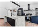 Modern kitchen with a waterfall island, stainless steel appliances, and floating shelves at 5501 Joyce Dr, Charlotte, NC 28215