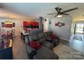 Open-concept living room featuring a gray sectional, ceiling fan, red accent pieces, and an eat-in kitchen at 8603 Westhope St, Charlotte, NC 28216