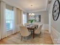 Formal dining room with modern chandelier, wainscoting, and neutral color palette at 9607 Kestral Ridge Dr, Charlotte, NC 28269