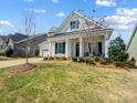 Inviting two-story home with a well-maintained lawn and covered front porch seating area at 10547 Skipping Rock Nw Ln, Concord, NC 28027