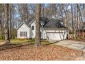 Two-story home featuring a grey roof, white siding, and a two-car garage surrounded by trees at 2157 Mill House Ln, Matthews, NC 28104