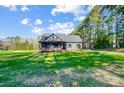 Charming home with a covered porch and manicured lawn set against a backdrop of mature trees and a blue sky at 437 Cedar Grove Rd, Clover, SC 29710