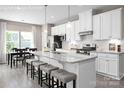 Open-concept kitchen with a large island, stainless steel appliances, and bar stool seating, seamlessly connected to the dining area at 510 Kenyon Dr, Denver, NC 28037