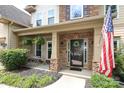 Charming front porch with stone accents, a cozy seating area, and an American flag displayed at 1800 Robbins Meadows Dr, Waxhaw, NC 28173