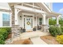 Inviting front porch with stone pillars, a cozy swing, decorative plants, and a welcoming wreath on the front door at 2150 Paddlers Cove Dr, Clover, SC 29710