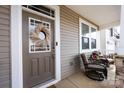 Inviting front porch with cozy seating, decorative wreath, and stone-accented columns at 3100 Cheyney Park Dr, Charlotte, NC 28269