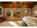 Bedroom with a brick accent wall, large windows providing natural light, and a stylish wooden four-poster bed at 4313 Kingswood Rd, Charlotte, NC 28226