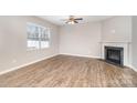 Bright living room with hardwood floors, a ceiling fan, a fireplace, and large windows for natural light at 10500 Bradstreet Commons Way, Charlotte, NC 28215