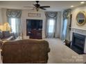 Cozy living room featuring a fireplace, ceiling fan, and neutral carpet at 1912 Darbywine Dr, Charlotte, NC 28216