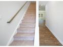 Inviting staircase featuring carpeted steps, a wooden handrail, and durable laminate flooring at 3168 Ora Smith Rd, Lincolnton, NC 28092