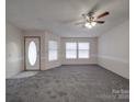 Bright living room featuring neutral carpeting, modern ceiling fan, and ample natural light from multiple windows at 40701 Nc 740 Hwy, New London, NC 28127