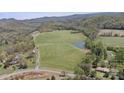 Expansive property featuring lush green fields, a serene pond, and distant mountain views from above at 447 Willow Pond Ln, Hiddenite, NC 28636