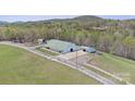 Aerial view of barn, outbuildings, white fencing, and surrounding landscape at 447 Willow Pond Ln, Hiddenite, NC 28636