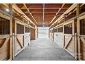 A rustic barn interior featuring wooden stalls and a concrete floor, providing a functional and charming equestrian facility at 447 Willow Pond Ln, Hiddenite, NC 28636