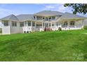 Elegant multi-story home featuring white siding, multiple balconies, and a lush green lawn at 447 Willow Pond Ln, Hiddenite, NC 28636