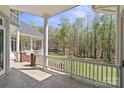 Covered porch with white pillars, tiled flooring, and scenic backyard views at 447 Willow Pond Ln, Hiddenite, NC 28636