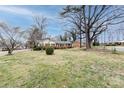 View of a charming one-story brick home from the street, surrounded by mature trees and lush lawns at 4601 Mendham Dr, Charlotte, NC 28215