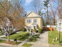 View of home with bright yellow siding, manicured lawn, long driveway, and mature trees at 4741 Eaves Ln, Charlotte, NC 28215