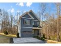 Charming two-story house featuring blue siding, a gray two-car garage, and a driveway leading up to the home at 615 W Stanly W St, Stanfield, NC 28163