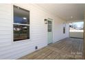 View of the covered front porch with wood decking, a light fixture, and a pale blue front door at 1018 Union St, Maiden, NC 28650