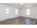 Bright, open living area featuring laminate flooring, two windows, and a door leading to the porch at 1018 Union St, Maiden, NC 28650