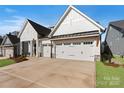 A modern farmhouse with white siding, a black roof, and a three-car garage on a concrete driveway at 1132 Meander Ln, Waxhaw, NC 28173