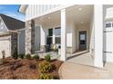 Inviting front porch with stone pillars, comfortable seating, tasteful landscaping, and a beautifully stained front door at 1132 Meander Ln, Waxhaw, NC 28173