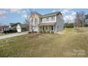 Inviting two-story home featuring landscaped yard, attached garage, and classic architectural details at 887 Pointe Andrews Dr, Concord, NC 28025