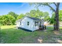 Quaint home with white vinyl siding and black shutters on a well-manicured lawn at 1413 Caldwell St, Gastonia, NC 28052