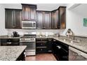 Well-equipped kitchen boasts granite countertops, stainless steel appliances, and dark wood cabinetry at 1809 Mill Creek Sw Ln, Concord, NC 28025