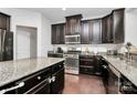 Modern kitchen with granite countertops, stainless steel appliances, dark wood cabinets, and hardwood floors at 1809 Mill Creek Sw Ln, Concord, NC 28025