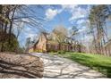 Brick home featuring a long drive way with grass on the right and a mix of trees and bushes at 25 Blenheim Ne Ct, Concord, NC 28025