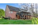 Back exterior of a brick home showcasing a screened porch, stairs, and a spacious green yard with trees at 2846 Snead Ne Ct, Conover, NC 28613