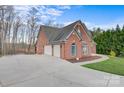 Brick home featuring a three-car garage and a long, curved driveway, surrounded by mature trees and landscaping at 2846 Snead Ne Ct, Conover, NC 28613