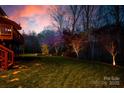 Picturesque backyard with trees highlighted with landscape lighting and a raised wood feature at 4232 Belle Meade Cir, Belmont, NC 28012
