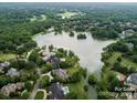 Stunning aerial view of a neighborhood with a lake surrounded by lush greenery and luxury homes at 5811 Old Well House Rd, Charlotte, NC 28226