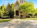 Inviting home featuring stone accents, mature trees, and manicured landscaping creating a picturesque setting at 5811 Old Well House Rd, Charlotte, NC 28226