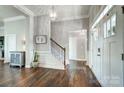 Elegant foyer featuring dark wood floors, white trim, staircase, and a modern light fixture at 6276 Artigas Dr, Fort Mill, SC 29707