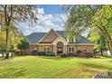 A stunning two-story brick home boasts a meticulously landscaped front yard, with mature trees and a well-manicured lawn at 2045 Driftwood Cir, Fort Mill, SC 29708