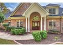 Elegant brick home showcasing an arched entryway with white columns and a custom wood front door at 2045 Driftwood Cir, Fort Mill, SC 29708